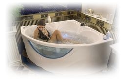 Ванна акриловая «Виктория 150» угловая гидромассажная с видом девушки лежащей в ванне